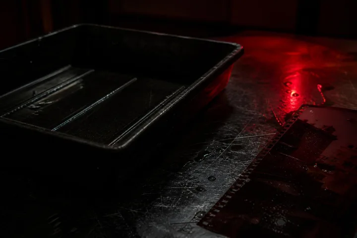Dettaglio di bacinella fotografica e negativi in una camera oscura abbandonata