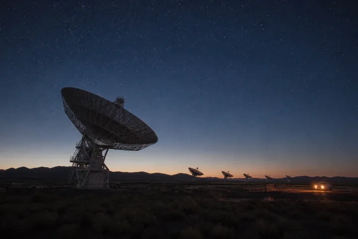 Radiotelescopi nel buio del deserto sotto un cielo stellato