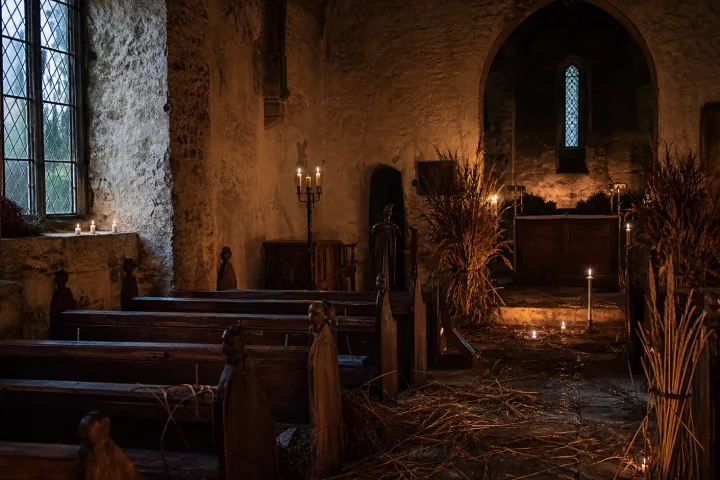 Vecchia chiesa rurale inglese con paglia sul pavimento e luce di candela