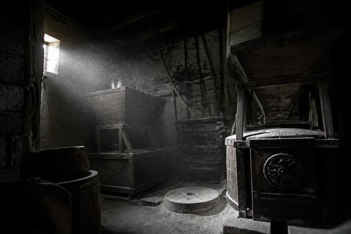 Mulino polveroso con vecchi ingranaggi di legno immersi in un fascio di luce bianca